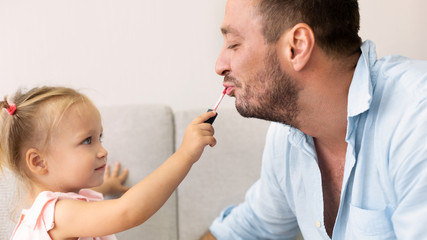 Cute girl applying makeup on her dad