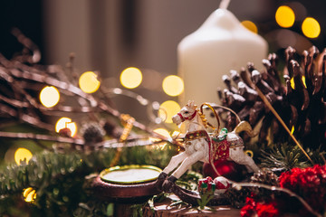 composition with fir branches, cones, Christmas toys and a wax white candle on a Christmas background. Festive Christmas decor with bokeh on the background. New Year, Christmas holiday card.
