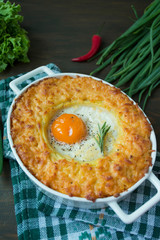 Potato casserole with bolognese. Baked potato casserole with egg and grated cheese in a ceramic oval baking sheet. Wooden dark background.