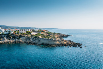 Fototapeta na wymiar Aerial view of beautiful nature cliff with villas or houses near Coral Bay beach in Paphos, Cyprus. Drone photo of mediterranean seascape background.