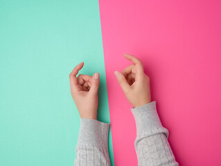 female hands on a green pink background, fingers in the gesture of holding the subject
