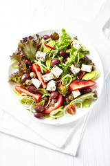 Salad with Olives, Tomatoes, Feta Cheese and Leek. Healthy Snack Idea. White wooden background. Top view. 
