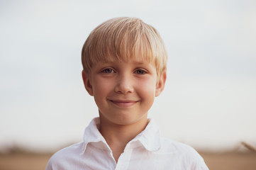 Face close - up of a boy of eight years. Portrait of a smiling boy in nature looking at the camera....