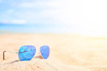 Fototapeta na wymiar Sunglasses on the sand with ocean and sky on background