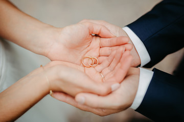 bride and groom holding wedding rings in their hands