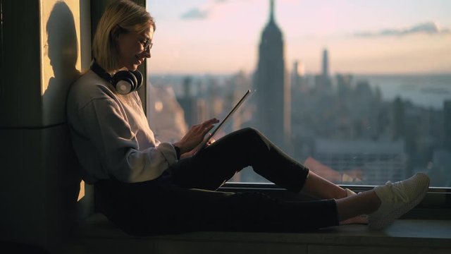 Attractive female blogger in optical spectacles for provide eyes protection connected to 4g wireless on digital tablet for online networking during social communication at web platform for millennials