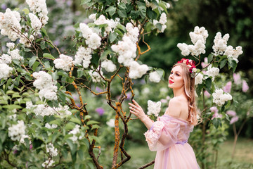 Beautiful romantic fairy girl in long dress in blooming spring garden. Gorgeous young model with perfect hairstyle in fairy forest. Fantasy art