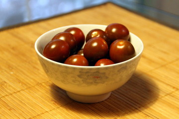 Small dark tomatoes in a white bowl