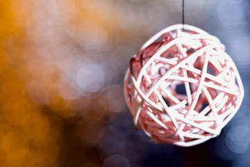 Rattan balls suspended on a thread. Against a background of bokeh with yellow-gray color.