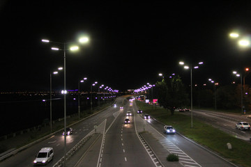 Fototapeta na wymiar Multiband highway in big city with going cars in night. Cars drive on highway
