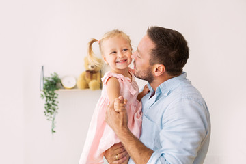 Caucasian dad holding and kissing his daughter