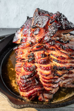 slices of rustic holiday honey glazed baked ham in cast iron pan