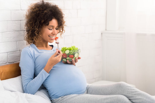 Happy pregnant woman eating natural vegetable salad
