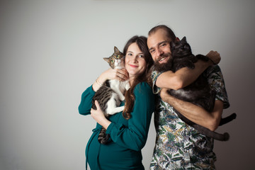 Man and woman holding a cat. Cat lovers. Two people hug two cats.  © suszczynski