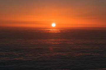 burning sun rising between clouds