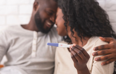 Happy afro couple holding pregnancy test with positive result - Powered by Adobe