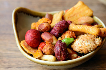 Nuts and cookies seasoned with salt and spices in a small plate on a wooden table. Great beer snack. Spicy snacks.