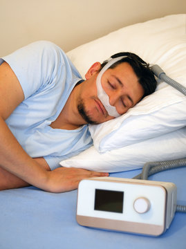 Healthy Young Man Wearing Under The Nose Nasal Mask And Using Cpap Machine For Sleeping Smoothly All Night Long On His Left Side Cross Arms Without Snoring. Sleep Apnea Therapy.