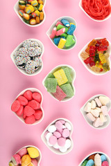 candies with jelly and sugar. colorful array of different childs sweets and treats on pink background