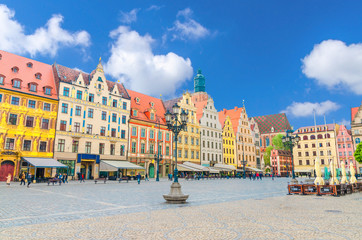 Obraz premium Row of colorful buildings with multicolored facade and St. Elizabeth Minor Basilica Garrison catholic Church on cobblestone Rynek Market Square in old town historical city centre of Wroclaw, Poland