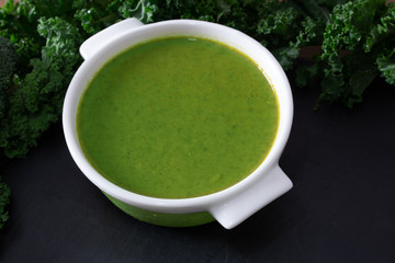 broth or cream of natural vegetables on the plate on black stone background