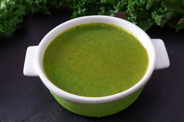 broth or cream of natural vegetables on the plate on black stone background