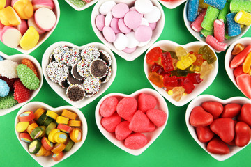 candies with jelly and sugar. colorful array of different childs sweets and treats on green background