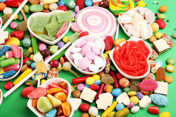 candies with jelly and sugar. colorful array of different childs sweets and treats on green background