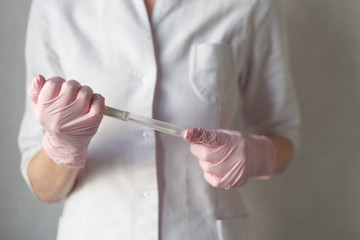 A gloved hand holding a medical swab tube