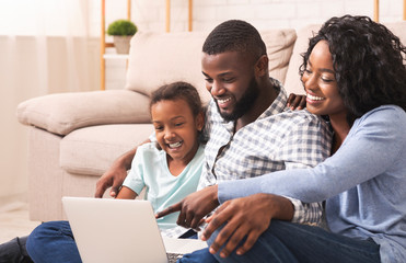 Joyful african american family using laptop at home together