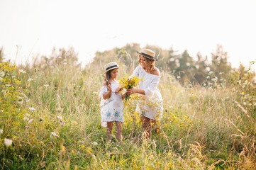 Naklejka na ściany i meble Mother and daughter having fun in the park. Happiness and harmony in family life. Beauty nature scene with family outdoor lifestyle. Mother's Day