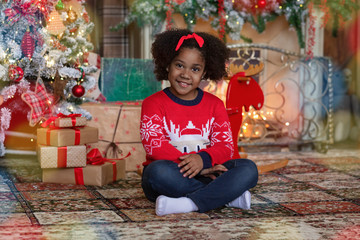 Portrait of little black girl sitting in room decorated for Christmas
