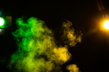 Green and yellow smoke with stage lights on black background