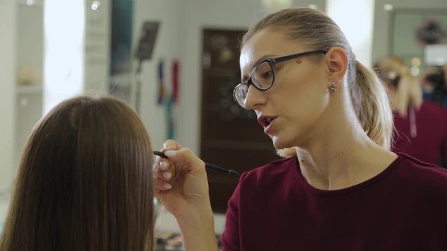 Professional makeup artist paints eyebrows to a client of a beauty salon.