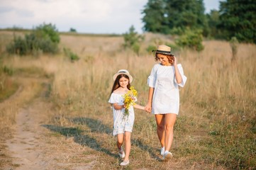 Naklejka na ściany i meble Stylish mother and handsome daughter having fun on the nature. Happy family concept. Beauty nature scene with family outdoor lifestyle. family resting together. Happiness in family life. Mothers day