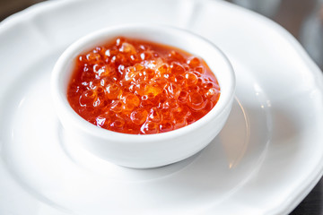 Red delicious caviar in the white small bowl served in the restaurant.