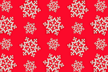 Pattern made of white snowflakes over red festive background.