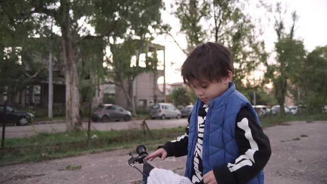 Caucasian toddler boy prepares to ride his bike and taunting  at camera outdoors
