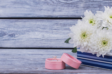 Flowers and box with diamond ring. Engagement ring in box and white chrysanthemums on wooden background. Marry me concept.