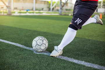 Soccer player speed run to shoot ball to goal on artificial turf. Soccer player training or...