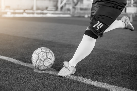 Black and white image of soccer player speed run to shoot ball to goal on artificial turf. Soccer player training for football match.
