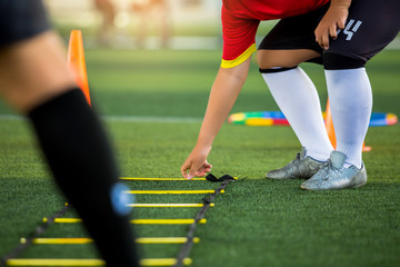 Young soccer player is putting the ladder drills for soccer trainng to run and jump. Ladder drills...