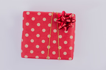 Red festive gift box isolated. Present box wrapped in red dotted paper and tied with golden ribbon.