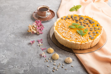 Traditional american sweet pumpkin pie decorated with mint, sesame and pumpkin seeds on a gray concrete background. side view, copy space.