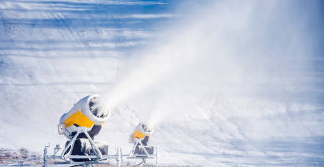 Snow cannon in winter mountains. Snow-gun spraying artificial ice crystals. Machine making snow.