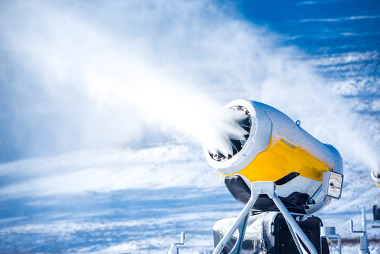Snow cannon in winter mountains. Snow-gun spraying artificial ice crystals. Machine making snow.