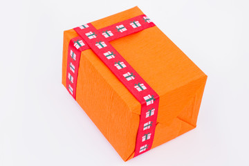 Orange gift box with red ribbon. Present box wrapped in orange paper and tied with red ribbon. Christmas gift background.