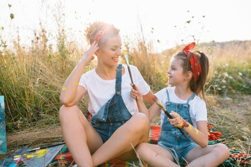 Young mother and her daughter have fun, mother's Day. smiling mother with beautiful daughter draws nature
