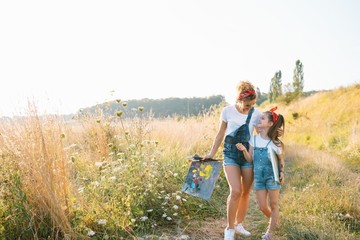 Fototapeta premium Młoda mama i córka bawią się, Dzień Matki. uśmiechnięta matka z piękną córką rysuje naturę