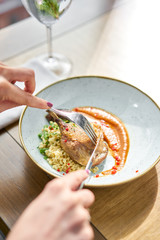 Lunch in a restaurant, a woman cuts delicious duck leg su-vide, with bulgur and onion marmalade. Barbecue restaurant menu, a series of photos of different meats